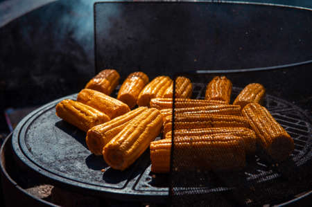 A professional cook prepares corn on the grill outdoor, food or catering conceptの写真素材
