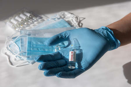 Coronavirus vaccine concept: covid-19 vaccine in doctor hand with blue protective gloves.の写真素材