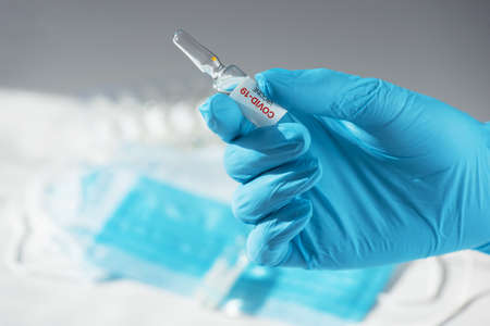 Coronavirus vaccine concept: covid-19 vaccine in hand with blue protective gloves.