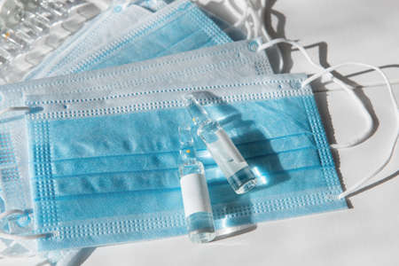 Coronavirus vaccine concept: covid-19 vaccine on the table with blue protective masks.
