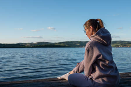 Young beautiful woman sitting on the pier