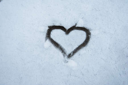 Drawn heart in a snow backgroundの写真素材