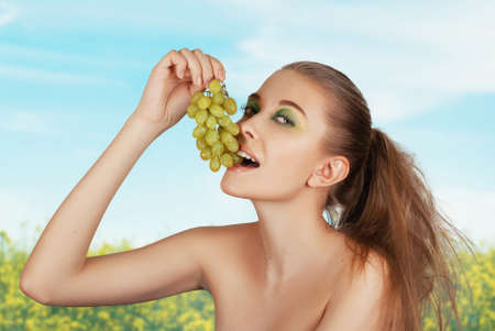 Beautiful young woman with grape bunchesの写真素材