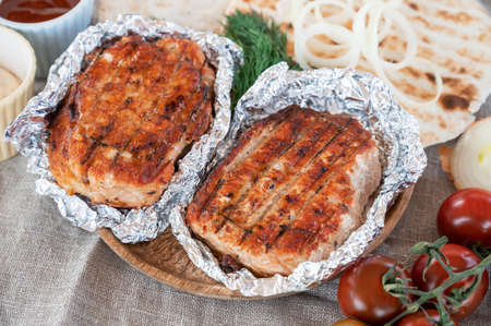 Grilled pork meat in foil with flapjack and vegetables
