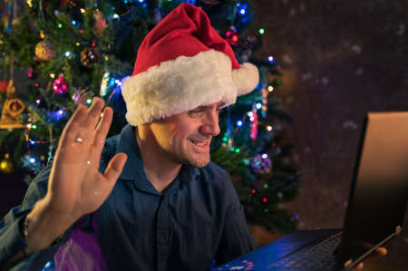 Happy man calling friends for Christmas using laptopの写真素材