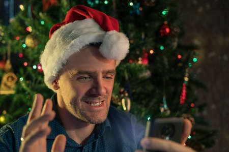 Happy man calling friends for Christmas using smartphoneの写真素材