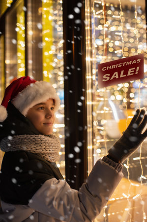 Boy in Santas hat looking in shop windowの写真素材