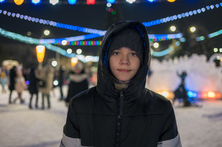 Happy teen boy posing in festive New Year eve street.