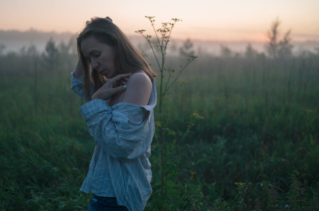 Woman in a field with misty fogの写真素材