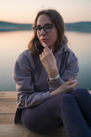 Woman sitting on the pier, closeup portrait, summer sunsetの写真素材