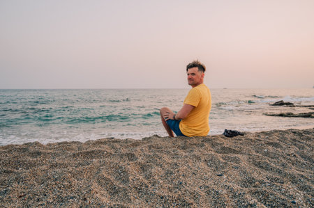 Man sits on the beach and looks at the sea in Alanya city, Turkey. Traveling or vacation conceptの写真素材