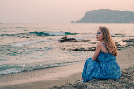 Woman sits on the beach and looks at the sea in Alanya city, Turkey. Traveling or vacation conceptの写真素材