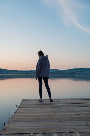 Woman on the pier at lake, summer sunsetの写真素材