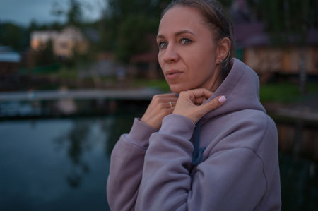 Woman sitting on the pier, closeup portrait, summer sunsetの写真素材