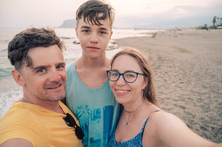 Happy family taking a photo on a beach at the sea in Alanya city, Turkey. Traveling or vacation...
