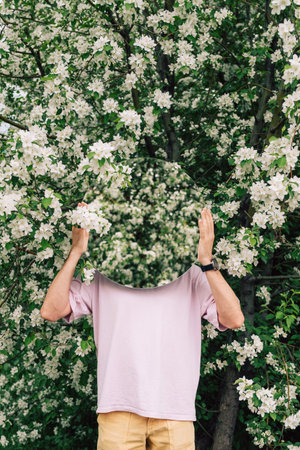 Creative male portrait with mirror in a blooming apples spring gardenの写真素材