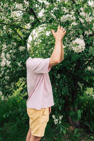 Creative male portrait with mirror in a blooming apples spring gardenの写真素材