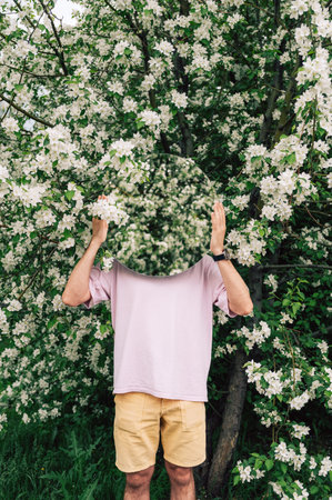 Creative male portrait with mirror in a blooming apples spring gardenの写真素材