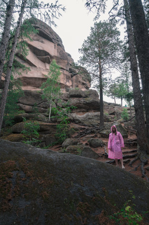 Woman in raincoat in the taiga forest and rocks of the Stolby nature reserve park, Krasnoyarsk, Russiaの写真素材