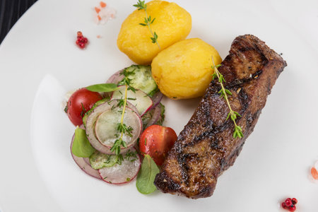 Grilled beef meat with potato and vegetables on white plateの写真素材