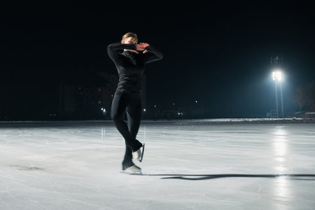 Beautiful young woman ice skating and performing short program over city outdoor ice arena. Winter activities conceptの写真素材