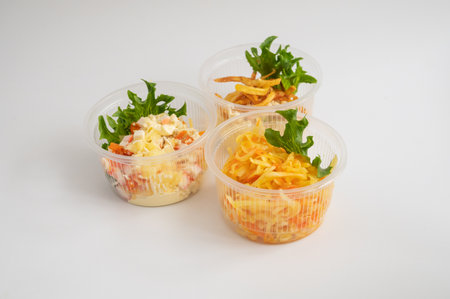 Three clear plastic containers with different salads, garnished with fresh greens.の写真素材