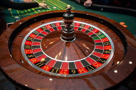 Casino, gambling and entertainment concept - roulette table and stack of poker chipsの写真素材