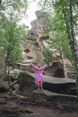 A woman wearing a pink raincoat in rocky forest. National park in the Krasnoyarsk regionの写真素材