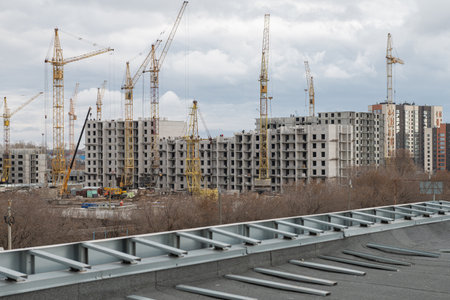 A large urban construction site with multiple tower cranes erecting modern apartment buildings under a cloudy sky.の写真素材