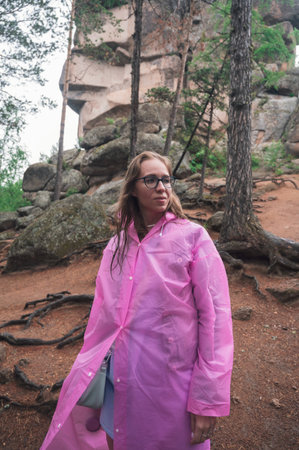 Woman in raincoat in the taiga forest and rocks of the Stolby nature reserve park, Krasnoyarsk, Russiaの写真素材