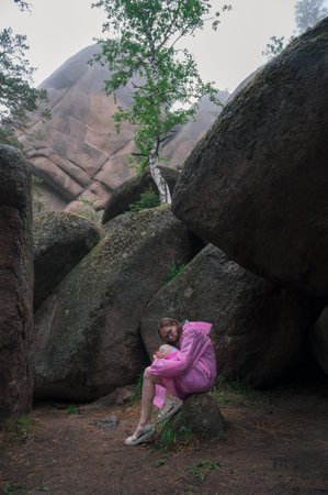 Woman in raincoat in the taiga forest and rocks of the Stolby nature reserve park, Krasnoyarsk, Russiaの写真素材