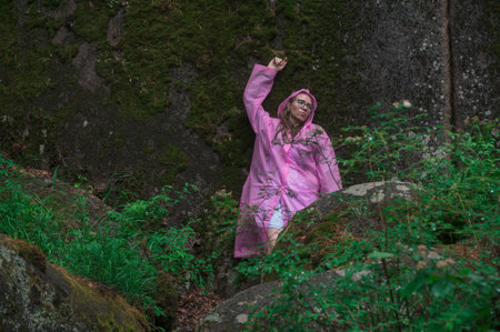 Woman in raincoat in the taiga forest and rocks of the Stolby nature reserve park, Krasnoyarsk, Russiaの写真素材
