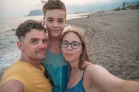 Happy family taking a photo on a beach at the sea in Alanya city, Turkey. Travelling or vacation conceptの写真素材
