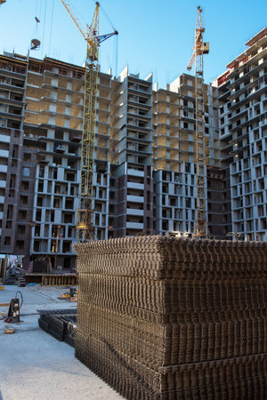 Ongoing construction of modern high-rise apartments with cranes, steel reinforcements, and...