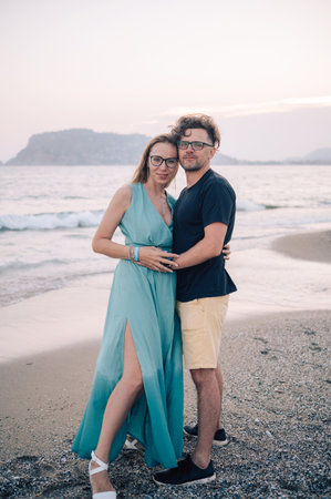 A smiling couple shares a joyful moment on the beach at sunset, the man and the woman near the sea wavesの写真素材
