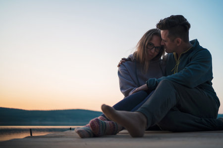 Couple on the pier at lake, summer sunsetの写真素材
