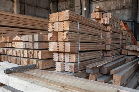 Large stacks of wooden beams and planks stored inside an industrial warehouse, ready for construction, carpentry, or woodworking projects.の写真素材