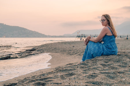 Woman sits on the beach and looks at the sea in Alanya city, Turkey. Travelling or vacation conceptの写真素材