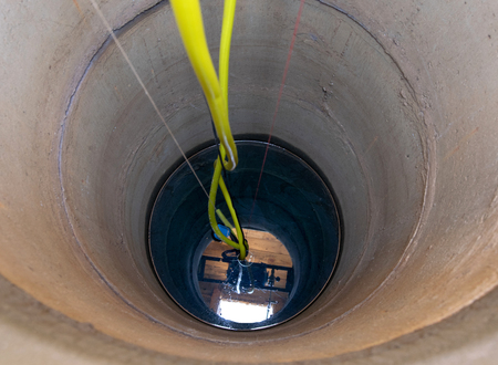 Concrete well with drinking water, with a pump and a hose.の写真素材