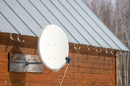 Old satellite dish on a wooden rural houseの写真素材