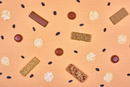 Dietary bars, marmalade, bread rolls and raisins on an orange backgroundの写真素材
