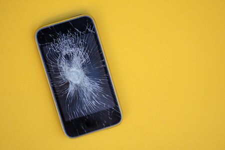Phone with cracked screen isolated against yellow backgroundの写真素材