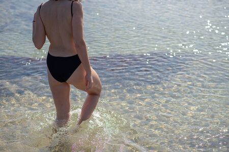 Cropped shot of woman heading into ocean for a swimの写真素材