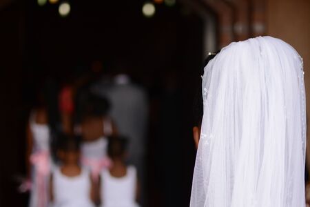 Bride shot from behind as she is about to enter church with brides maid ahead