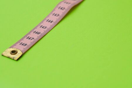 Close up of measuring tape against green background