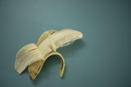 Banana with condom isolated against teal backgroundの写真素材