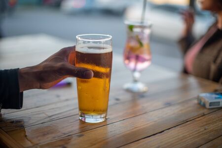 Close up shot of hand holding glass of beer with blurred backgroundの写真素材