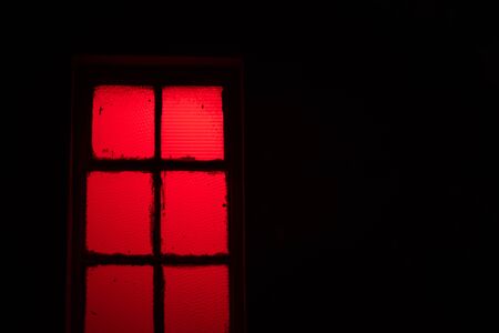 Red light shining through window at nightの写真素材