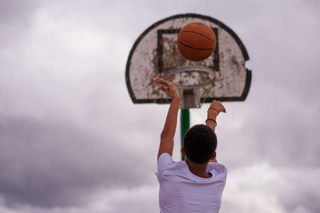 Rear view of young boy shooting basketball towards hoop