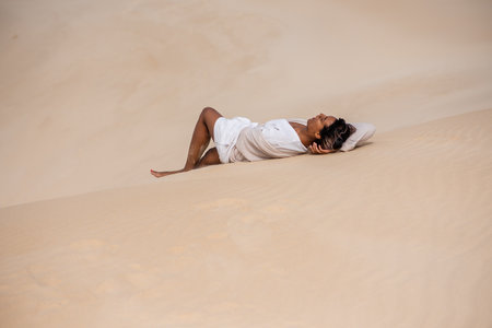 Woman seen laying on sand dunesの写真素材